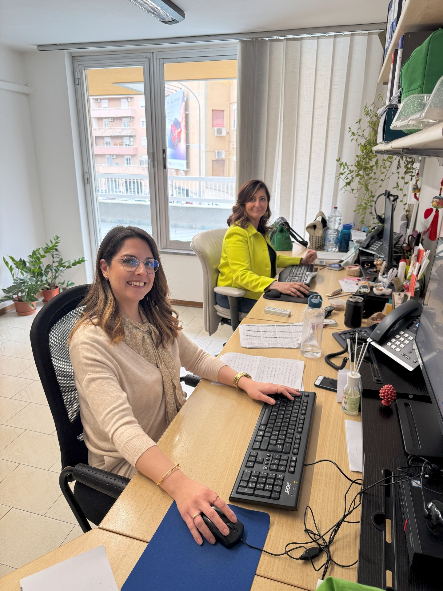 Two members of the Tour of Sicily Travel Expert Team smiling at their desks
